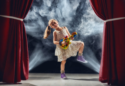 girl playing guitar on stage