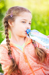 Obraz premium Little cute girl on the nature drinks water