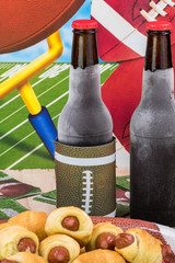 Bottles of cold beer and plate with pigs in blanket on the table decorated for football party.