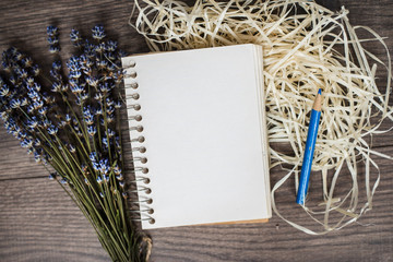 Old vintage notepad with empty white pages laying on a wooden table. Shavings and a bouquet of lavender.