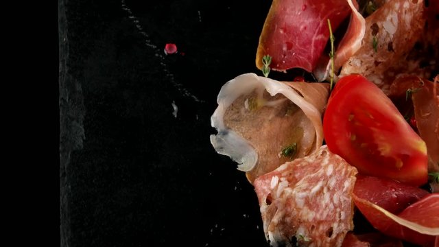 Meat slices, ham, salami, bacon, on the black stone tray, closeup, loop