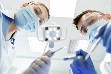 close up of dentist and assistant at dental clinic