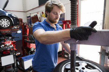 Mechanic in car workshop exchanging tire