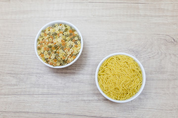 bowls of noodles, pasta stars and spaghetti on a wooden table
