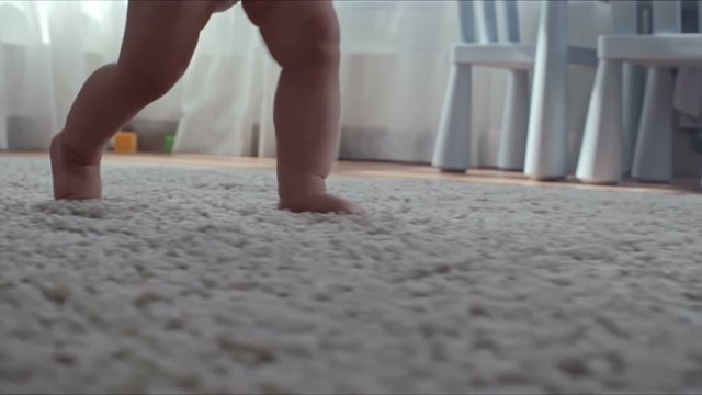 Closeup of barefoot legs of little child learning how to step on the carpet with help of mother