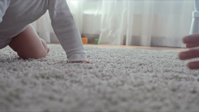 Closeup of barefoot legs of little child walking by herself on the carpet and then falling down and crawling to mother