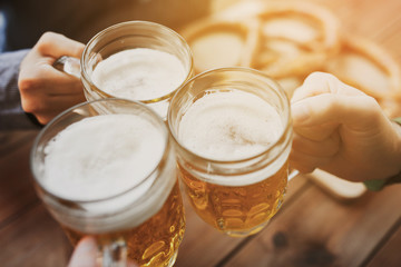 close up of hands with beer mugs at bar or pub