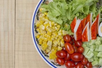 Closeup fresh vegetable salad on vintage plate with space on wood background