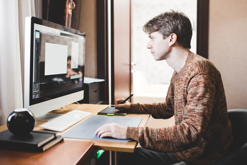 Young man at home using a computer, freelance developer or designer working