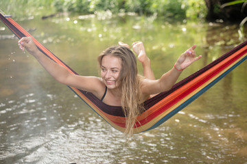 beautiful girl riding in a hammock over the water.