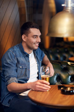 happy man drinking draft beer at bar or pub