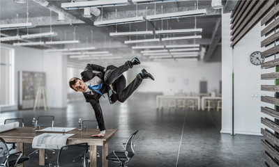 Jumping businessman in office . Mixed media