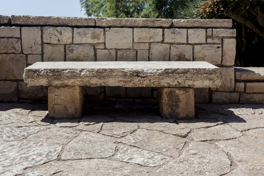 Stone white fence behind the stone bench on a stone ground outdoors