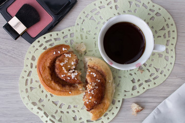 Overhead view of homemade cinnamon roll and a cup of black coffee 
