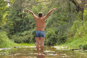 a man meditating in the middle of the water forest river
