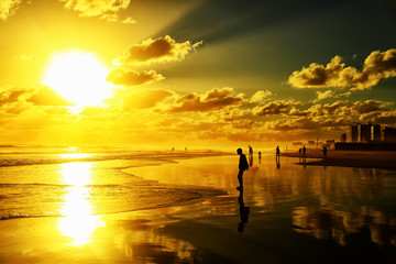 Silhouettes of people at the ocean beach during a beautiful sunset