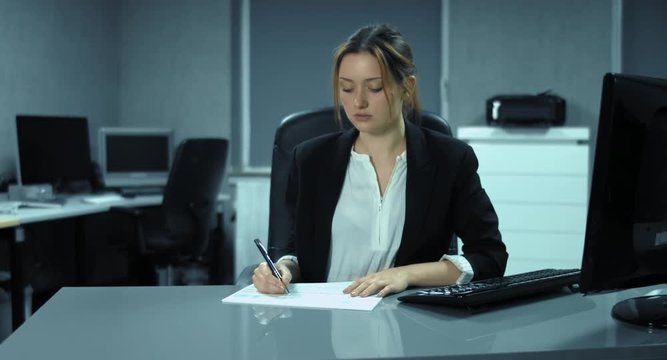 4K: Bürostress. Eine Frau arbeitet an einem Stapel Dokumenten und hofft auf Feierabend. Die Chefin legt ihr einen neuen Stapel auf den Tisch.