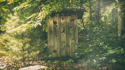 Rural Outhouse. A typical old fashioned outhouse bathroom in a wooded, forest area.
