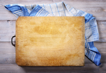 Cutting board and dish towel on old wooden background