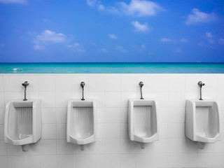 Sanitary ware set on the wall at the public toilet with sea background.Old and dirty sanitary with...