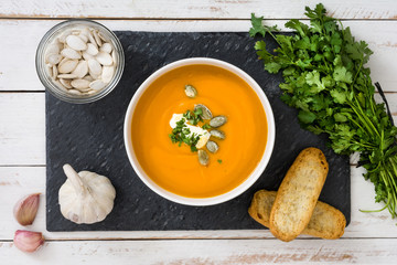 Pumpkin soup on slate plate and a white wooden table

