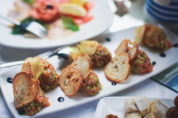 Beautifully decorated catering banquet table with different food snacks and appetizers with sandwich, caviar, fresh fruits on corporate open-air party event or wedding celebration
