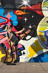 Fitness model posing by the graffiti wall with ropes