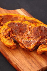 Raw lamb chops with a mint sauce marinade on a wooden chopping board