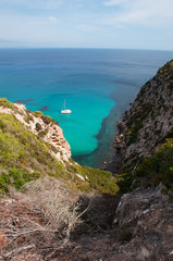 Formentera, Isole Baleari: un catamarano nel Mar Mediterraneo con vista sulla macchia mediterranea...