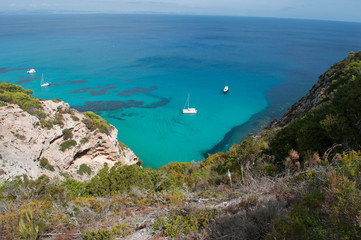 Formentera, Isole Baleari: un catamarano e un motoscafo nel Mar Mediterraneo con vista sulla macchia mediterranea e le scogliere il 5 settembre 2010