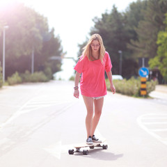 Girl im Sonnenschein auf der Strasse skaten