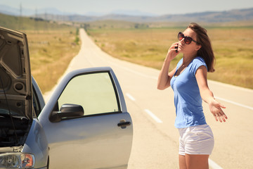 Woman with a broken car on the road using phone