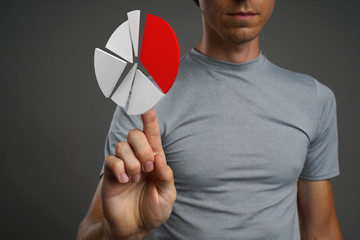 Man in t-shirt working with pie chart on grey background.