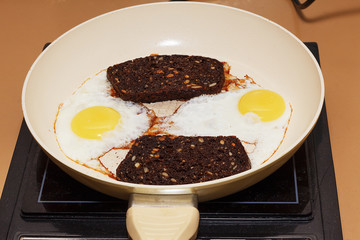 eggs fried in a pan with slices of black bread