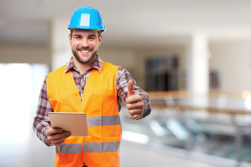 Smiling manual worker in blue helmet gesture thumb up
