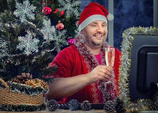 Merry and Bright: Middle-Aged Man Embraces Christmas Spirit at Work Desk, Raising Glass Amid Tinsel and Ornaments.