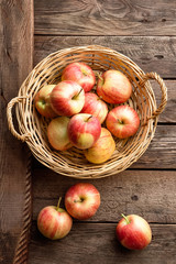 Fresh red apples in wicker basket on wooden table.