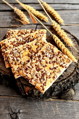 Wholesome cookies with sunflower seeds, flax seeds and sesame seeds. Vegetarian cookies snack. Ears of wheat on old wooden background