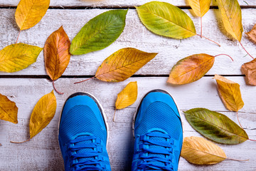 Blue sports shoes. Colorful autumn leaves. White wooden backgrou