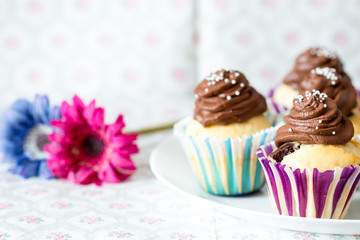 Vanilla cupcake with chocolate topping and flowers.