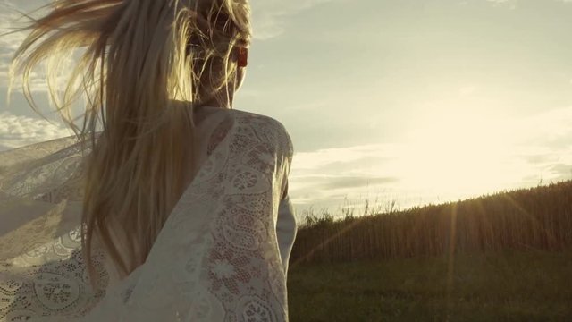 Young female in boho style is running at sunset. Attractive girl in white.