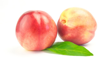 Ripe juicy nectarines with green leaves isolated on white background