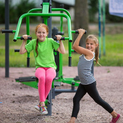 Fototapeta na wymiar Funny little girls is engaged in sports equipment outdoor.