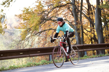 Fototapeta premium Young sportsman riding his bicycle outside in sunny autumn natur