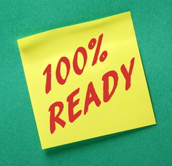 The phrase 100% Ready in red text on a yellow sticky note as a reminder to be prepared 