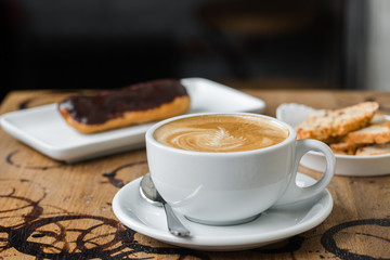 cappuccino flatwhite coffee with eclair on table