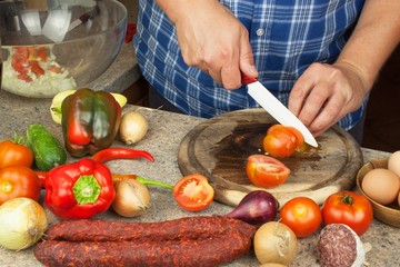 Chef sliced onion on board. Preparing vegetables for healthy salad. Slicing onions and tomatoes. Fresh vegetables in the kitchen.

