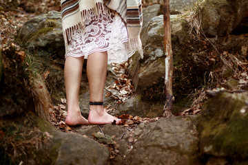 beautiful boho woman legs with pikestaff in woods