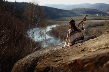 beautiful boho woman shaman  sitting on rocks