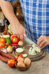 Chef sliced onion on board. Preparing vegetables for healthy salad. Slicing onions and tomatoes. Fresh vegetables in the kitchen.
